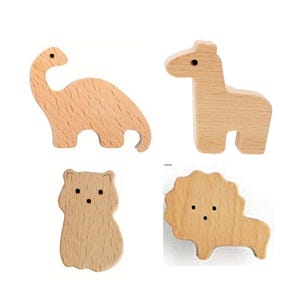 May include: Four wooden animal figures: a dinosaur, giraffe, bear, and lion. Each figure is cut from light-colored wood and features simple, rounded shapes. The dinosaur has a long neck, the giraffe stands upright, the bear is stout, and the lion has a mane.