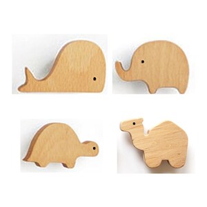 May include: Four wooden animal shapes: a whale, an elephant, a turtle, and a camel. Each animal is made of light-colored wood with a simple design and a small black dot for an eye. The shapes are arranged against a white background.