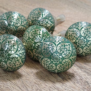 Könnte beinhalten: Sechs grüne und goldene dekorative Schrankknöpfe mit komplizierten Blumenmustern.