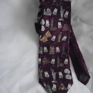 May include: A purple silk tie with a pattern of famous landmarks and the year 2000 printed on it.