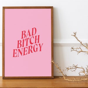 Puede incluir: Un p&oacute;ster rosa enmarcado con el texto "BAD BITCH ENERGY" en letras rojas.