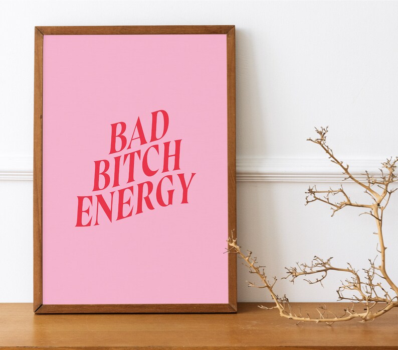 Puede incluir: Un p&oacute;ster rosa enmarcado con el texto "BAD BITCH ENERGY" en letras rojas.