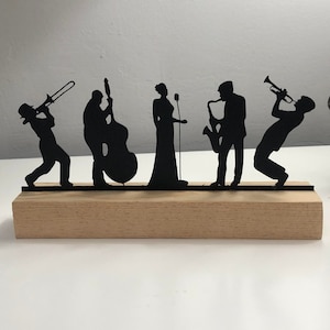 Op de afbeelding: Een zwart metalen silhouet van een jazzband op een houten basis. De band bestaat uit een trompettist, een saxofonist, een zanger, een bassist en een trombonist.