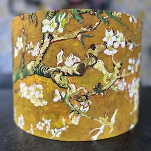 May include: A cylindrical lampshade featuring a printed reproduction of an almond blossom painting. The design displays thick, textured brushstrokes in shades of mustard yellow, olive green, and brown, accented by white flower blossoms.
