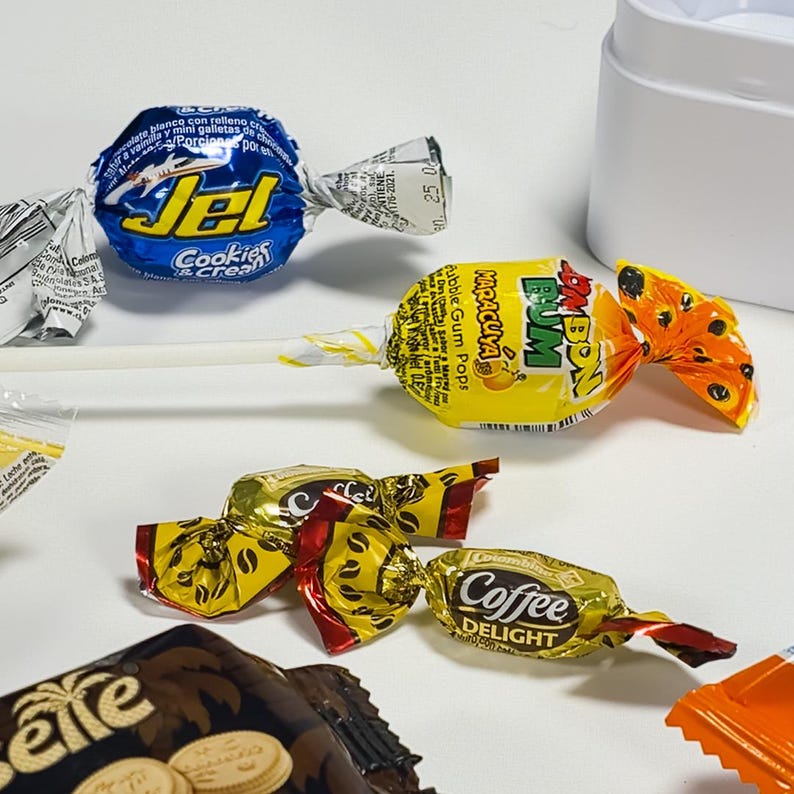May include: Assortment of wrapped candies, including lollipops and individually wrapped sweets. The lollipops feature colorful wrappers with text, and the candies include coffee and cookie flavors. The image is a close-up shot of the treats.