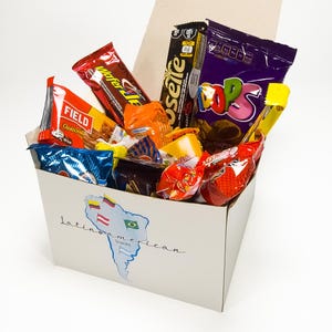 May include: A white box filled with various Latin American snacks. The box features a map of South America with flags and the text "Latin American Snacks". The snacks include colorful wrappers and packaging.