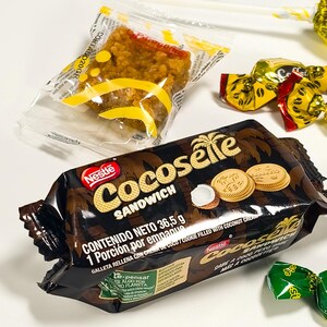 May include: A package of Nestle Cocoselle Sandwich cookies with coconut cream, a small wrapped snack, and individually wrapped candies. The Cocoselle package is brown with gold lettering and images of cookies and coconut.