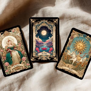 Puede incluir: Tres cartas de tarot con dise&ntilde;os ornamentados. Una carta presenta a una mujer con un vestido verde, etiquetada como "La Emperatriz". Otra muestra una escena iluminada por la luna, etiquetada como "La Luna". La tercera representa un sol y un jinete, etiquetada como "El Sol".