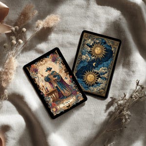 Puede incluir: Dos cartas de tarot con ilustraciones ornamentadas. Una carta presenta una figura con t&uacute;nicas azules y moradas, la otra representa una escena celestial con soles, nubes y una luna creciente. Las cartas tienen un borde negro y est&aacute;n sobre un fondo neutro.