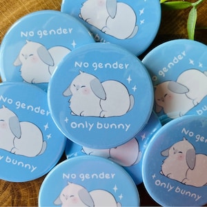 Könnte beinhalten: Eine Sammlung runder, blauer und weißer Knöpfe mit einem Cartoon-Kaninchen und dem Text "No gender + only bunny".