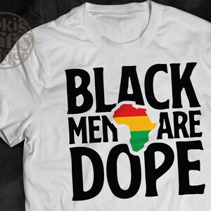 以下が含まれることがあります： 黒い文字で「Black Men Are Dope」と書かれた白いTシャツ。赤い、黄色い、緑色のアフリカ大陸の輪郭が、「men」と「are」の間に中央に配置されています。