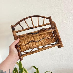 May include: A vintage bamboo wine rack with a curved top and wavy accents. The rack is made of natural bamboo and has a warm, brown color. It is designed to hold multiple bottles of wine.