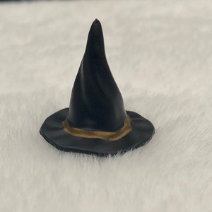 May include: A black witch hat with a gold trim. The hat is made of a soft, pliable material and has a pointed top.