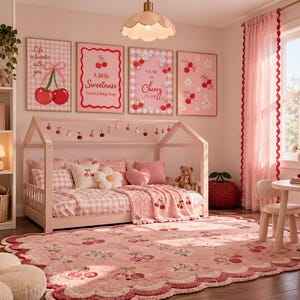 Könnte beinhalten: Ein Schlafzimmer mit einem hellen Holz-Hausbettgestell, rosa karierter Bettwäsche, Kissen mit Kirschmotiven und einem flauschigen Teppich mit Kirschmuster. Vier gerahmte Wandbilder zeigen Kirschillustrationen und Text, ergänzt durch rosa Vorhänge.