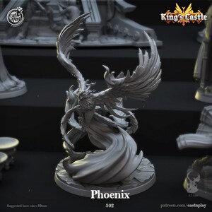 May include: A gray 3D printed miniature of a Phoenix, a mythical bird with wings outstretched, in a dramatic pose. The miniature is on a round base with a textured surface. The text "Phoenix 502" is printed below the miniature.