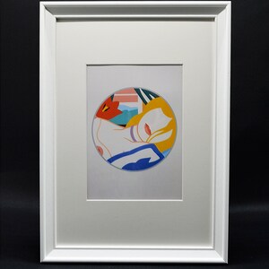 Puede incluir: Una impresión enmarcada de una pintura abstracta colorida con el rostro de una mujer en un círculo. La pintura está realizada en tonos de rojo, naranja, amarillo, azul y blanco.