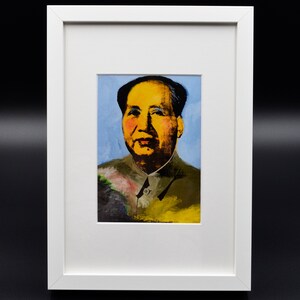 Puede incluir: Una pintura enmarcada de un hombre con la cara amarilla y el pelo negro. El fondo es azul y el hombre lleva una camisa verde y amarilla.