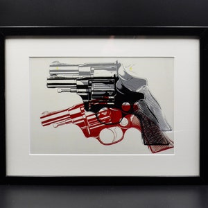 Puede incluir: Una impresión artística enmarcada que presenta una ilustración estilizada de un revólver. La obra de arte utiliza una combinación de rojo, negro, gris y blanco, con la forma del arma superpuesta y parcialmente transparente. La impresión está enmarcada en negro.