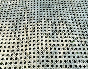 Könnte beinhalten: Weißes Rohrgeflecht, ein gewebtes Material, das für Stuhlsitze und -lehnen verwendet wird, auf einer grasbewachsenen Oberfläche ausgelegt.