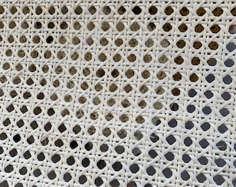 Könnte beinhalten: Nahaufnahme von weißem Cannage-Gewebe, einem gewebten Material, das für Stuhlsitze und -lehnen verwendet wird. Das Material ist in einem engen, gleichmäßigen Muster gewebt.