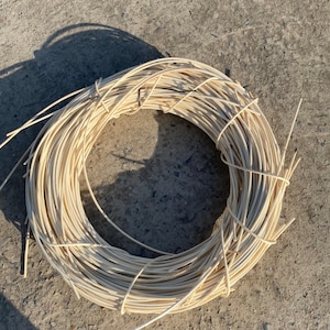 Op de afbeelding: Een close-up van een spoel natuurlijke kleur riet, een materiaal dat wordt gebruikt voor het weven van manden en meubels.