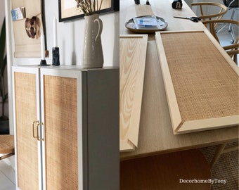 Könnte beinhalten: Ein weißer Schrank mit zwei Türen, jede Tür mit einer geflochtenen Rattanplatte. Der Schrank steht auf einem Holzboden. Der Schrank wird mit neuen Rattanplatten renoviert. Die neuen Platten sind auf einem Tisch mit Holzmaserung zu sehen. Die Platten sind aus geflochtenem Rattan und haben eine natürliche braune Farbe.