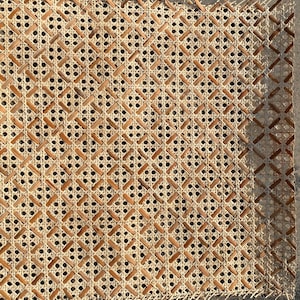 May include: Close-up of a woven cane webbing material, often used for chair seats. The material is made of natural fibers and has a light brown color.