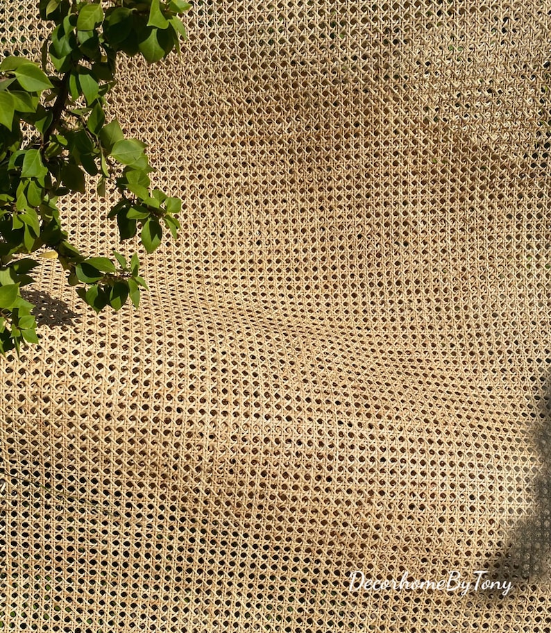 May include: Close-up of a woven cane material with a diamond pattern. The material is a light tan color and has a slightly curved shape. Green leaves are visible in the upper left corner. The text "DecorhomeByTony" is in the bottom right corner.