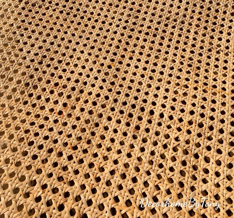 May include: Close-up of a woven cane material with a repeating pattern of small, evenly spaced holes. The natural, light brown material is tightly woven, creating a textured surface. The image is well-lit, highlighting the intricate details of the weave.