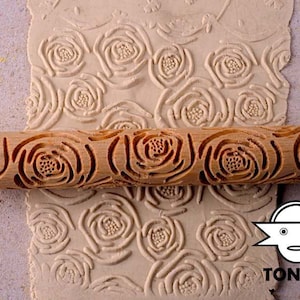 Könnte beinhalten: Ein Nudelholz aus Holz mit einem in die Oberfläche geschnitzten Rosenmuster. Das Nudelholz wird verwendet, um dekorative Muster in Teig, Fondant oder Ton zu erstellen.