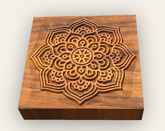 May include: A square wooden block with a carved mandala design. The mandala is intricate and detailed, with a brown colour.