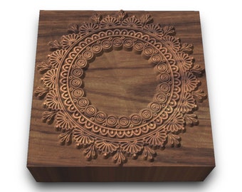 May include: A wooden block with a carved circular design. The design features intricate details, including swirls, dots, and floral patterns. The block is a dark brown color and has a smooth, polished finish.