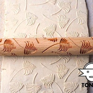 May include: A wooden rolling pin with a carved design of palm leaves. The rolling pin is used to create an embossed pattern on dough or fondant.