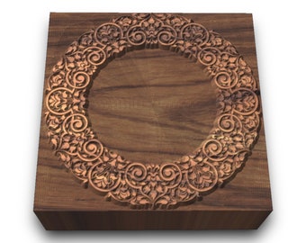 Può includere: Un blocco quadrato di legno con un design circolare scolpito, intricato, di colore marrone chiaro. Il design è un motivo floreale con volute e foglie.