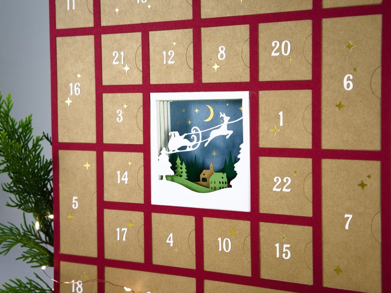 May include: A Christmas advent calendar with a red background and individual brown squares, each numbered. One square features a cut-out scene of Santa's sleigh. Gold star accents are scattered throughout the calendar.