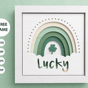 May include: A white frame with a green and cream rainbow design and the word "Lucky" cut out of the bottom. A four-leaf clover is in the center of the rainbow.