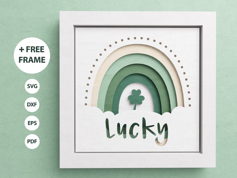 May include: A white frame with a green and cream rainbow design and the word "Lucky" cut out of the bottom. A four-leaf clover is in the center of the rainbow.