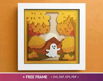 May include: A layered paper art piece in a white frame. The artwork depicts a fall landscape with a white ghost figure, trees with orange and yellow leaves, and a mountain. The frame includes the text "+ FREE FRAME".