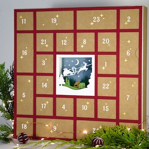 May include: A Christmas advent calendar with 24 numbered doors. The calendar is made of brown cardboard with red borders. A central window reveals a winter scene with a reindeer-pulled sleigh. Gold star accents and greenery decorate the calendar.