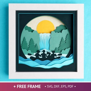 May include: A papercraft scene of a waterfall with a group of people in a raft. The scene is framed in a white frame with a black mat. The scene is set against a blue background.