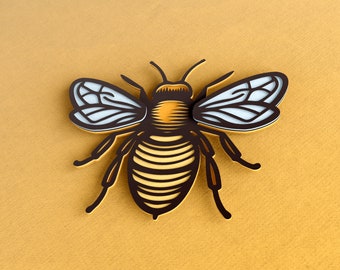 May include: A black and yellow bee with white wings, illustrated in a vintage style. The bee is on a yellow background.