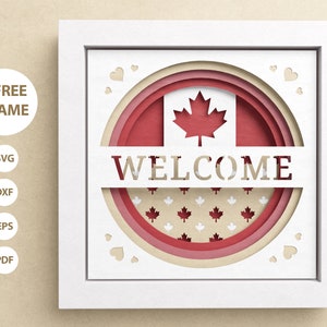 Könnte beinhalten: Ein weißer Rahmen mit einem mehrschichtigen Papierschnitt-Design in Rot, Weiß und Beige der kanadischen Flagge mit dem Wort "WELCOME" in der Mitte. Das Design ist von kleinen weißen Herzen umgeben.
