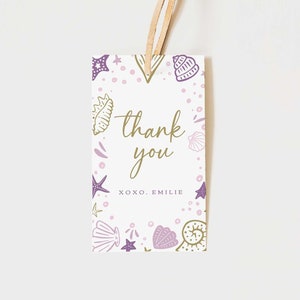 May include: A white thank you tag with a purple and gold seashell design. The text reads "thank you xoxo, Emilie".