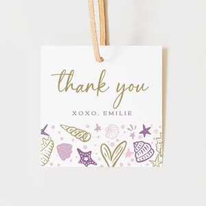 May include: Square white gift tag with a gold "thank you" script and the name "Emilie". The bottom border features seashell and starfish illustrations in purple and gold. A tan ribbon is attached at the top.