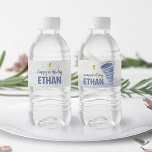 May include: Two clear plastic water bottles with personalized labels. The labels are blue and white with a lightning bolt and the text "happy birthday ETHAN". One label features a blue and white tornado graphic.
