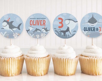 May include: Four blue and white cupcake toppers with a shark and the text "Happy Birthday Oliver" and "Oliver is 3".
