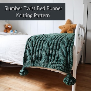 May include: A dark green knitted bed runner with a cable knit design and two matching tassels. The bed runner is draped over a white bed frame. The text "Slumber Twist Bed Runner Knitting Pattern" is at the top.