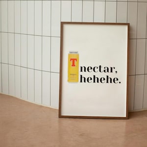 Puede incluir: Un cartel enmarcado con una lata amarilla con un logotipo "T" rojo y las palabras "nectar, hehehe". El cartel está en un marco marrón, contra una pared de azulejos blancos y un suelo marrón claro.