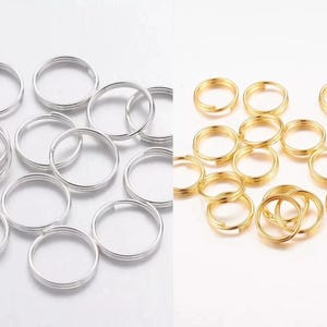 May include: A selection of silver and gold-coloured split key rings. The silver rings are on the left, and the gold rings are on the right. The rings are round and have a split to allow for easy attachment.