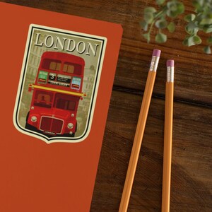 May include: A red double-decker bus with the word "LONDON" on the front and side. The bus is in front of a building with the word "LONDON" on a sign. The bus has the number "3" on the front and the words "COVENT GARDEN" on the side.